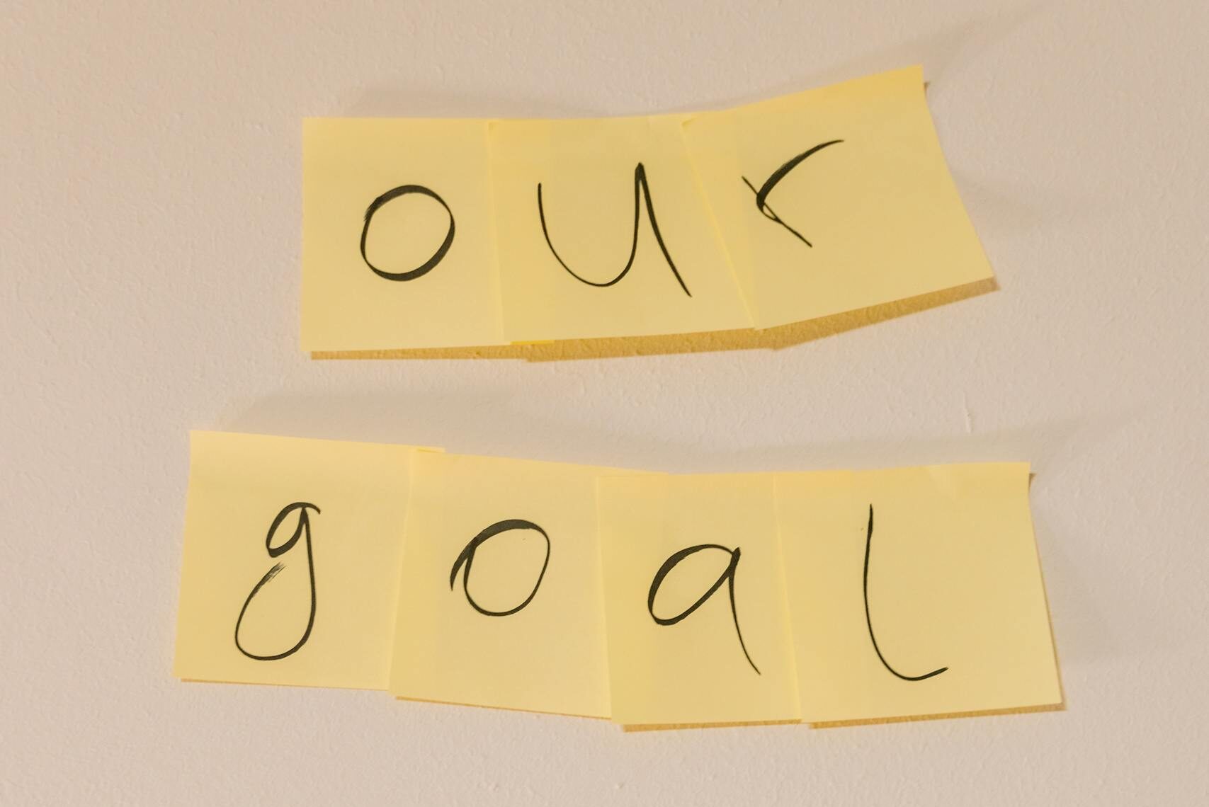 Sticky notes with the text 'our goal' on a wall emphasizing objectives.